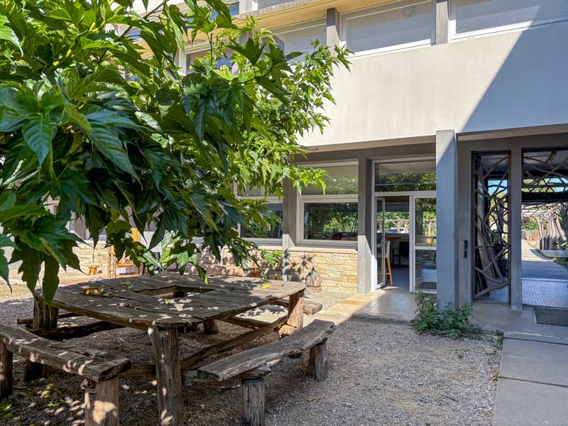 Ancienne cabane en bois rustique, aménagée en espace de formation en extérieur à la CFP-MFR La Ferrière, entourée de végétation verdoyante.
