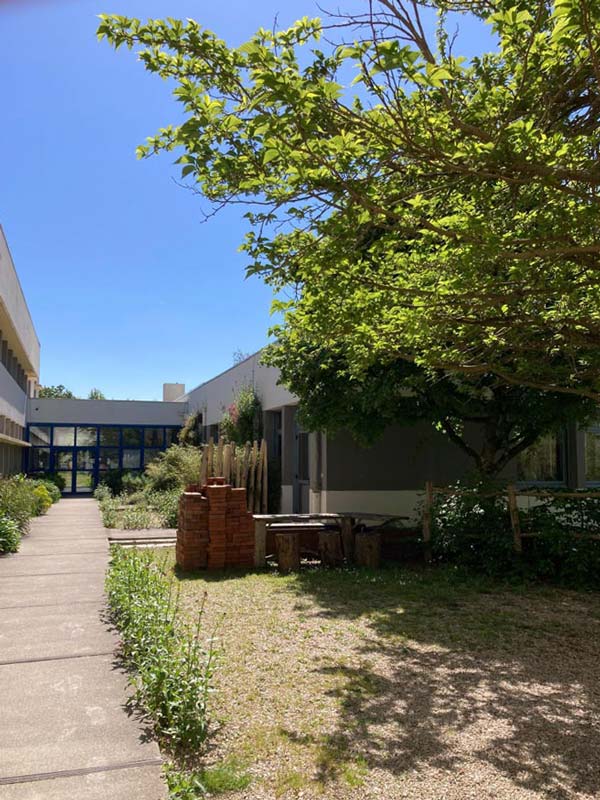 Chemin menant au CFP-MFR La Ferrière avec espace vert et bâtiment en arrière-plan.